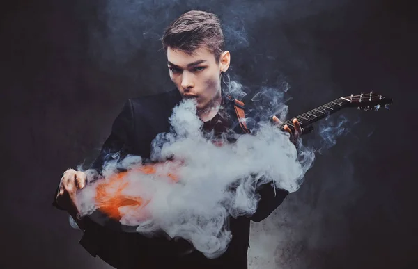 Cara atraente está tocando guitarra acústica e fumando — Fotografia de Stock