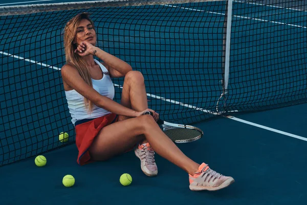 Красивая женщина отдыхает на теннисном корте — стоковое фото