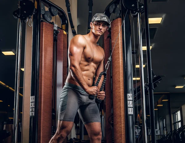 Muskularny Człowiek robi ćwiczenia z aparaturą treningową — Zdjęcie stockowe