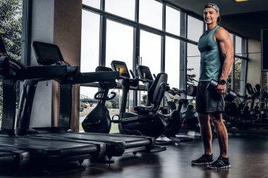 Adam spor salonunda dambıllarla antrenman yaptı.