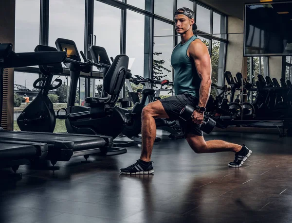 Adam spor salonunda dambıllarla antrenman yaptı.