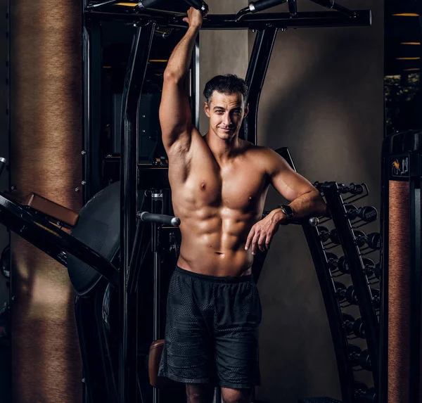 Homem muscular está fazendo exercícios com aparelho de treinamento — Fotografia de Stock
