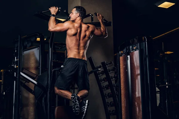 Homem muscular está fazendo exercícios com aparelho de treinamento — Fotografia de Stock