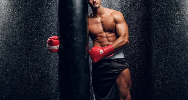 Potente maschio è in posa con sacco da boxe — Foto Stock