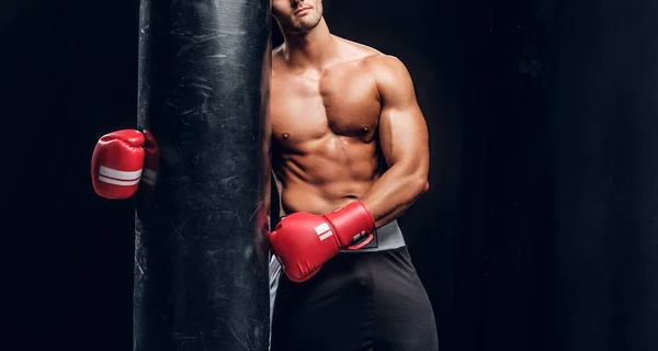 Powerful male is posing with punching bag — Stock Photo, Image