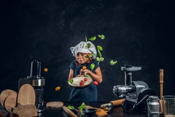 Little girl is tossing vegetables on the pan — Stock Photo, Image