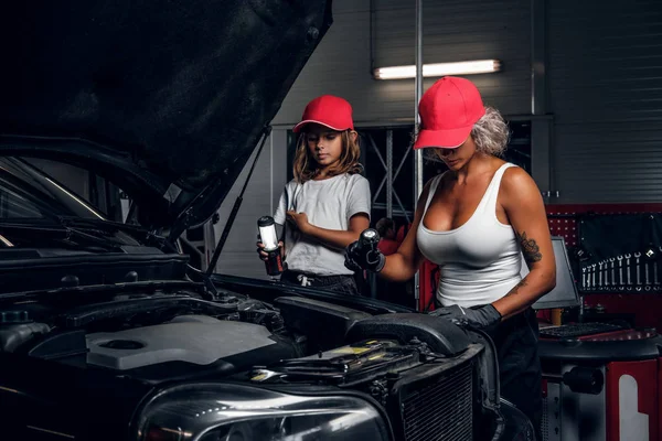 Vrouw toont auto's motor voor klein meisje — Stockfoto