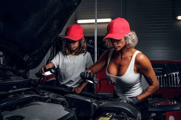 Женщина показывает автомобильный двигатель для маленькой девочки — стоковое фото
