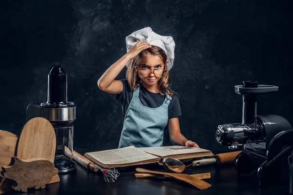 Little girl is reading recipe book — Stock Photo, Image