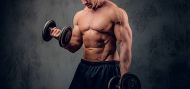 Güçlü erkek karanlık arka plan üzerinde halter ile egzersiz yapıyor