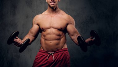 Güçlü erkek karanlık arka plan üzerinde halter ile egzersiz yapıyor