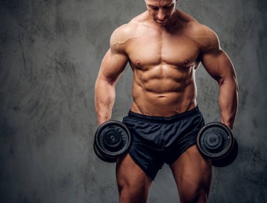 Güçlü erkek karanlık arka plan üzerinde halter ile egzersiz yapıyor