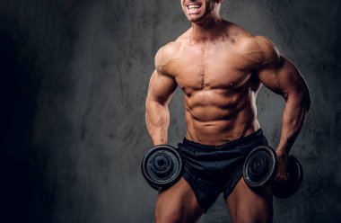 Güçlü erkek karanlık arka plan üzerinde halter ile egzersiz yapıyor