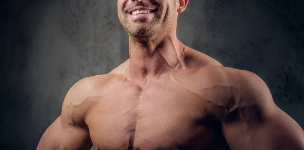 Krachtige bodybuilder is poseren op de donkere achtergrond — Stockfoto