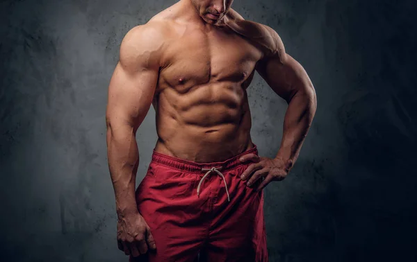 Krachtige bodybuilder is poseren op de donkere achtergrond — Stockfoto