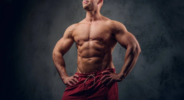 Mächtiger Bodybuilder posiert vor dunklem Hintergrund — Stockfoto