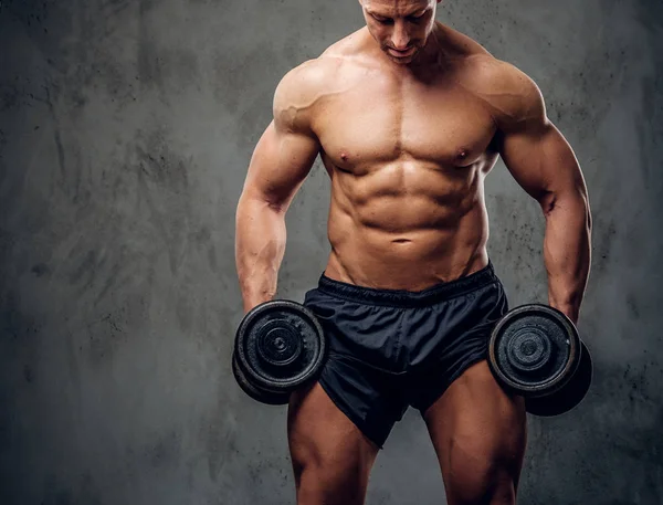 Güçlü erkek karanlık arka plan üzerinde halter ile egzersiz yapıyor