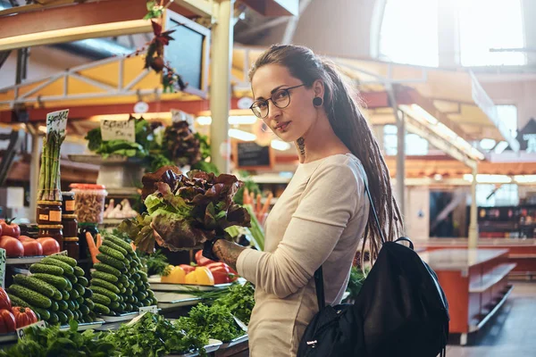 Jeune femme tatouée choisit des légumes de saison au marché — Photo