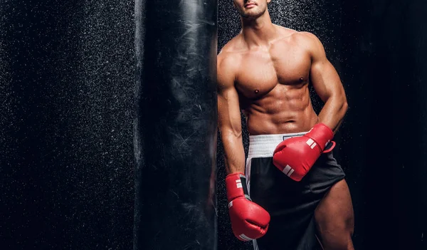 Potente maschio è in posa con sacco da boxe — Foto Stock