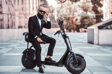 Modern adam yeni elektro scooter'ının üzerinde oturuyor.