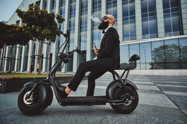 Modern adam yeni elektro scooter'ının üzerinde oturuyor.