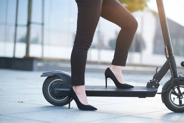 Mulher está montando scooter usando sapatos de salto alto — Fotografia de Stock