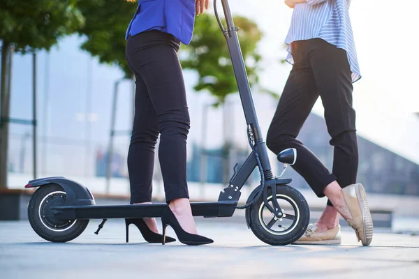 Benen van twee vrouwtjes met elektrische scooter — Stockfoto