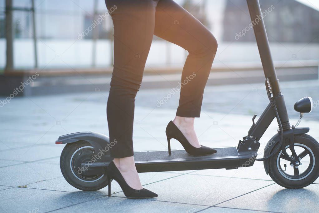 Woman is riding scooter wearing hight heels shoes