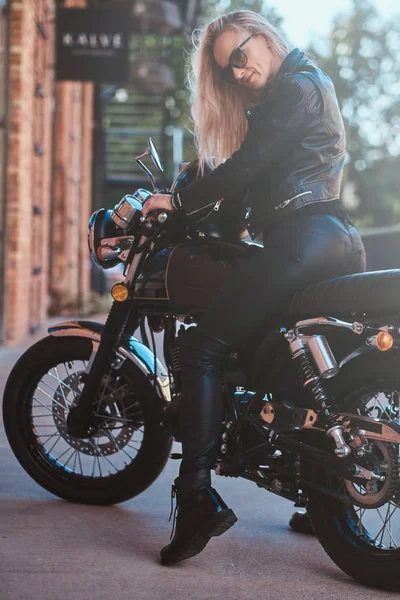 Portrait of sexy matyre female biker next to brick building — Stock Photo, Image