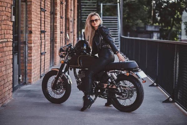 Potret seksi matyre biker perempuan di sebelah bangunan bata — Stok Foto