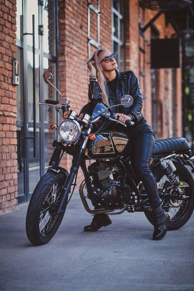 Retrato de sexy maduro feminino motociclista ao lado de tijolo edifício — Fotografia de Stock