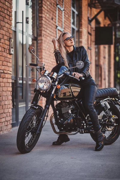 Knappe vrouwelijke Biker poseren voor fotograaf met haar motorfiets — Stockfoto