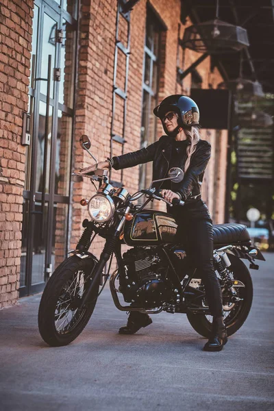 Przystojny kobieta rowerzysta jest stwarzające dla fotograf z jej motocykl — Zdjęcie stockowe