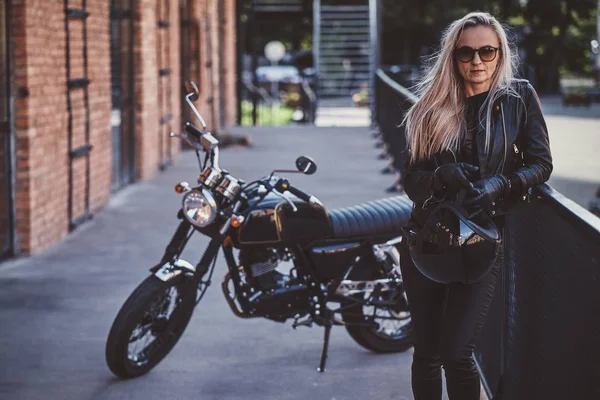 Knappe vrouwelijke Biker poseren voor fotograaf met haar motorfiets — Stockfoto