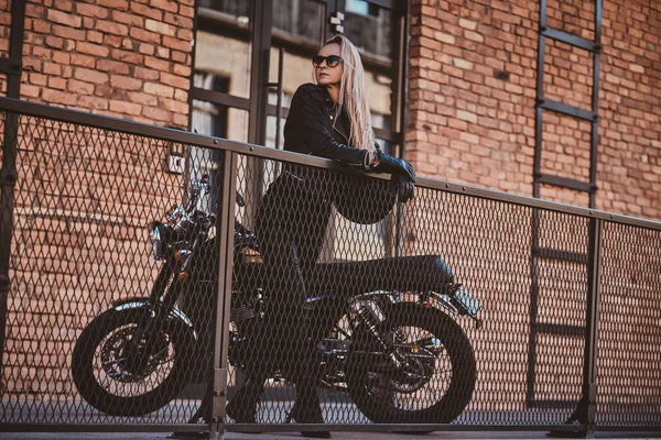 Mujer guapo motorista está posando para el fotógrafo con su moto — Foto de Stock