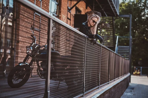 Mujer guapo motorista está posando para el fotógrafo con su moto — Foto de Stock