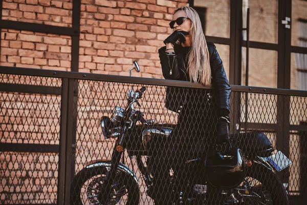Knappe vrouwelijke Biker poseren voor fotograaf met haar motorfiets — Stockfoto