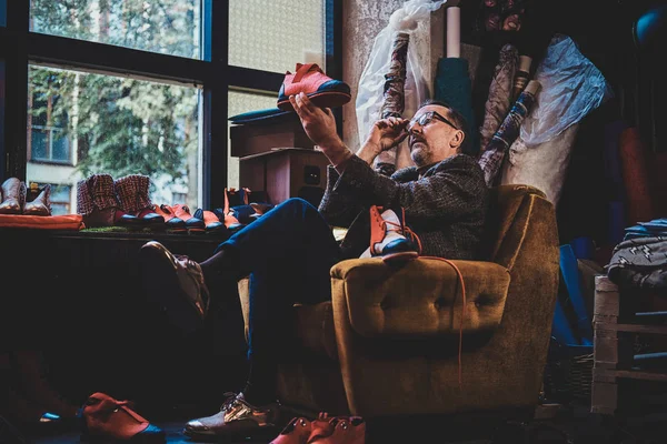 Fabricante de botas está sentado no sofá — Fotografia de Stock