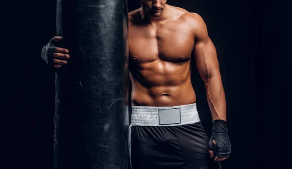 Powerful male is posing with punching bag — Stock Photo, Image