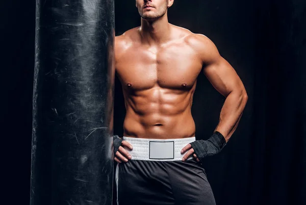 Powerful male is posing with punching bag — Stock Photo, Image