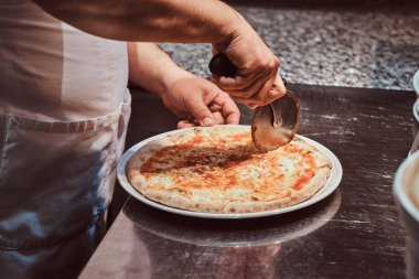 Şef taze hazırlanmış pizza kesiyor