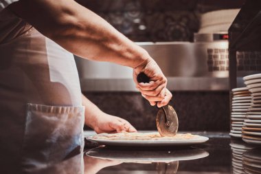 Şef taze hazırlanmış pizza kesiyor