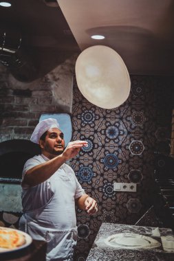 Şef mutfağa pizza atıyor.