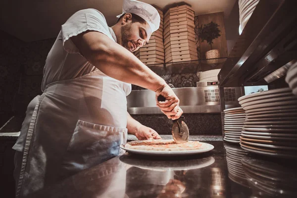 Chef-kok is snijden vers bereide pizza — Stockfoto