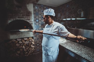 Şef fırına pizza koyuyor.