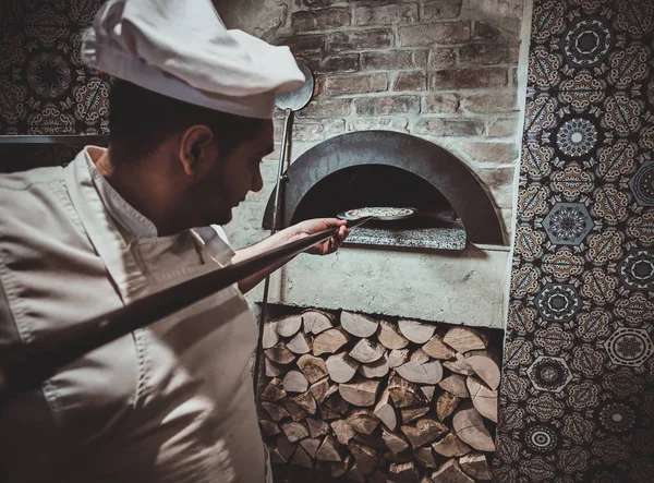 Chef-kok zet pizza in de oven — Stockfoto