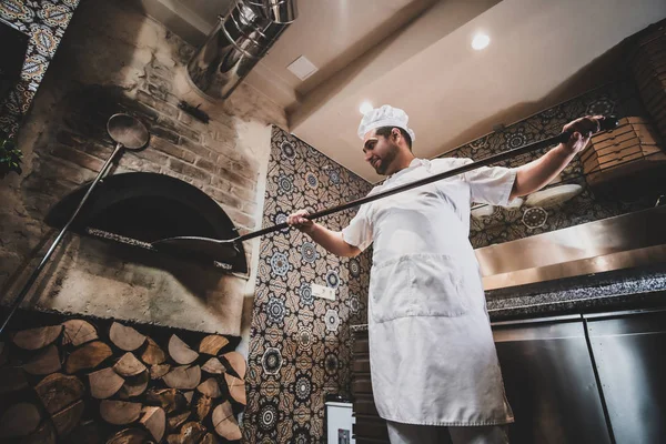 Шеф-повар удаляет пиццу из духовки — стоковое фото