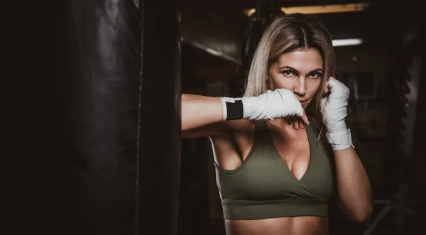 Portrait of female boxer on her training with punching bag