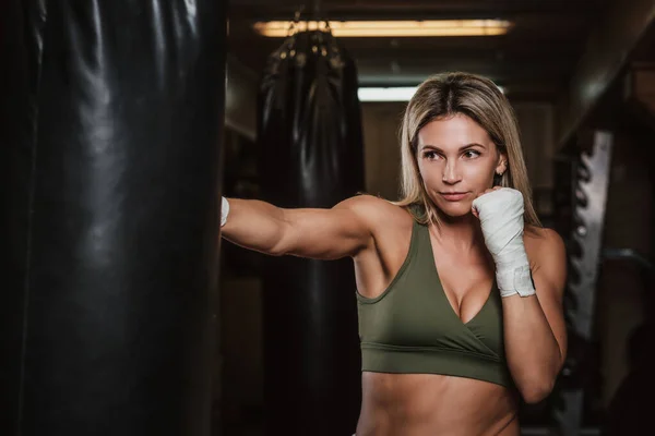 Retrato de boxeadora femenina en su entrenamiento con saco de boxeo — Foto de Stock