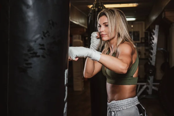 Portrait of female boxer on her training with punching bag — 스톡 사진